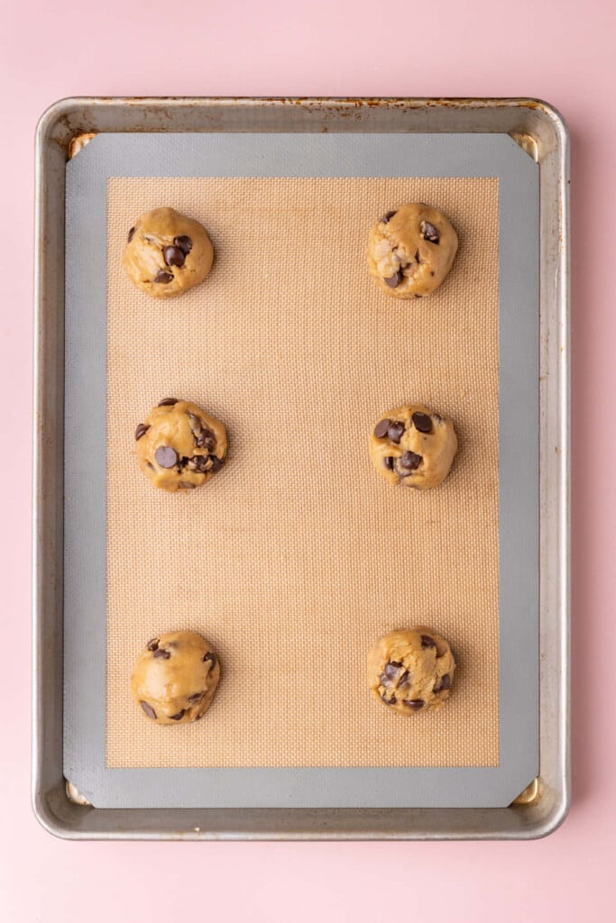 Olive oil chocolate chip cookies lined up on a baking tray ready for the oven.