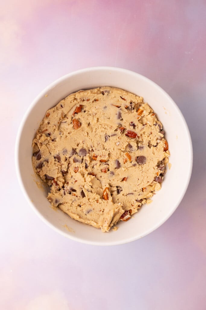 Chocolate chip pecan cookie dough in a mixing bowl with colorful background.