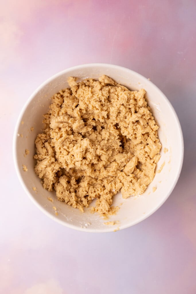 Cookie dough in a mixing bowl before adding chocolate chips and chopped pecans.
