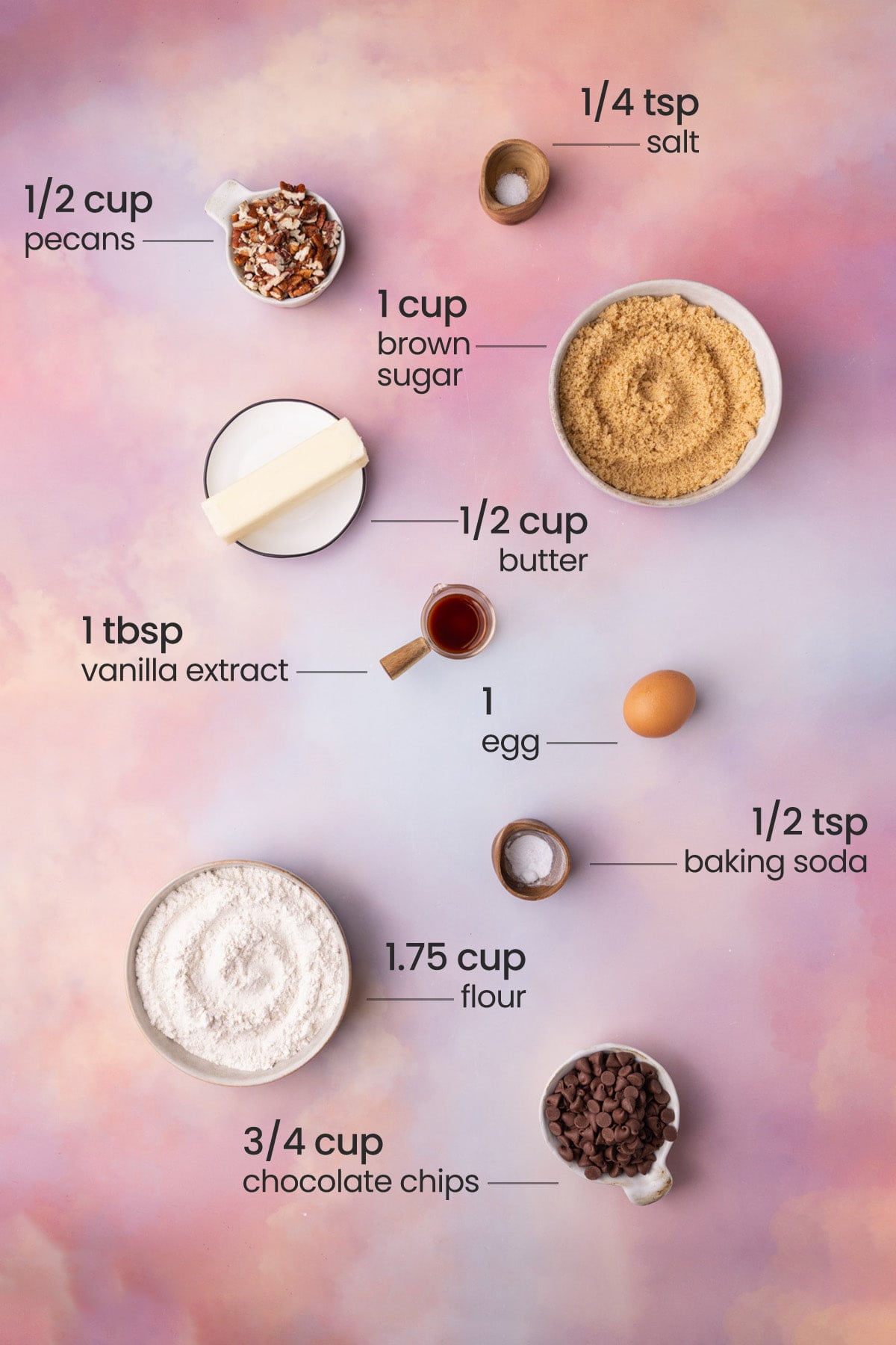 Overhead view of the ingredients needed for pecan chocolate chip cookies - salt, pecans, brown sugar, butter, vanilla extract, egg, baking soda, flour, and chocolate chips.