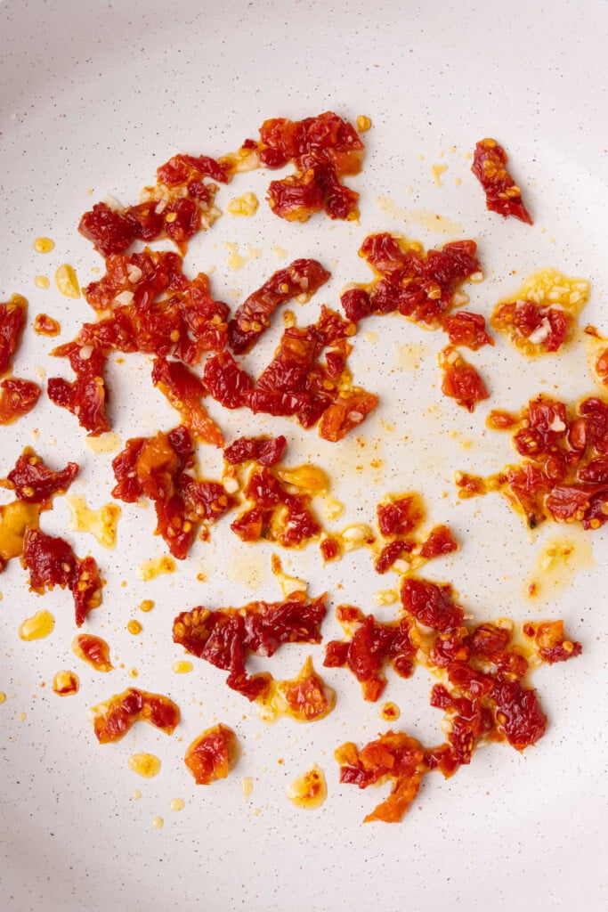 Diced sun-dried tomatoes and minced garlic cooking in oil.