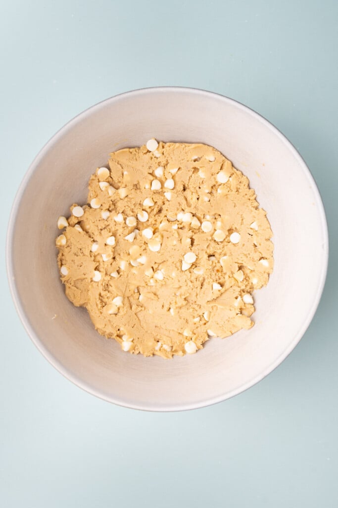 Cookie dough with white chocolate chips ready to form cookies for baking.