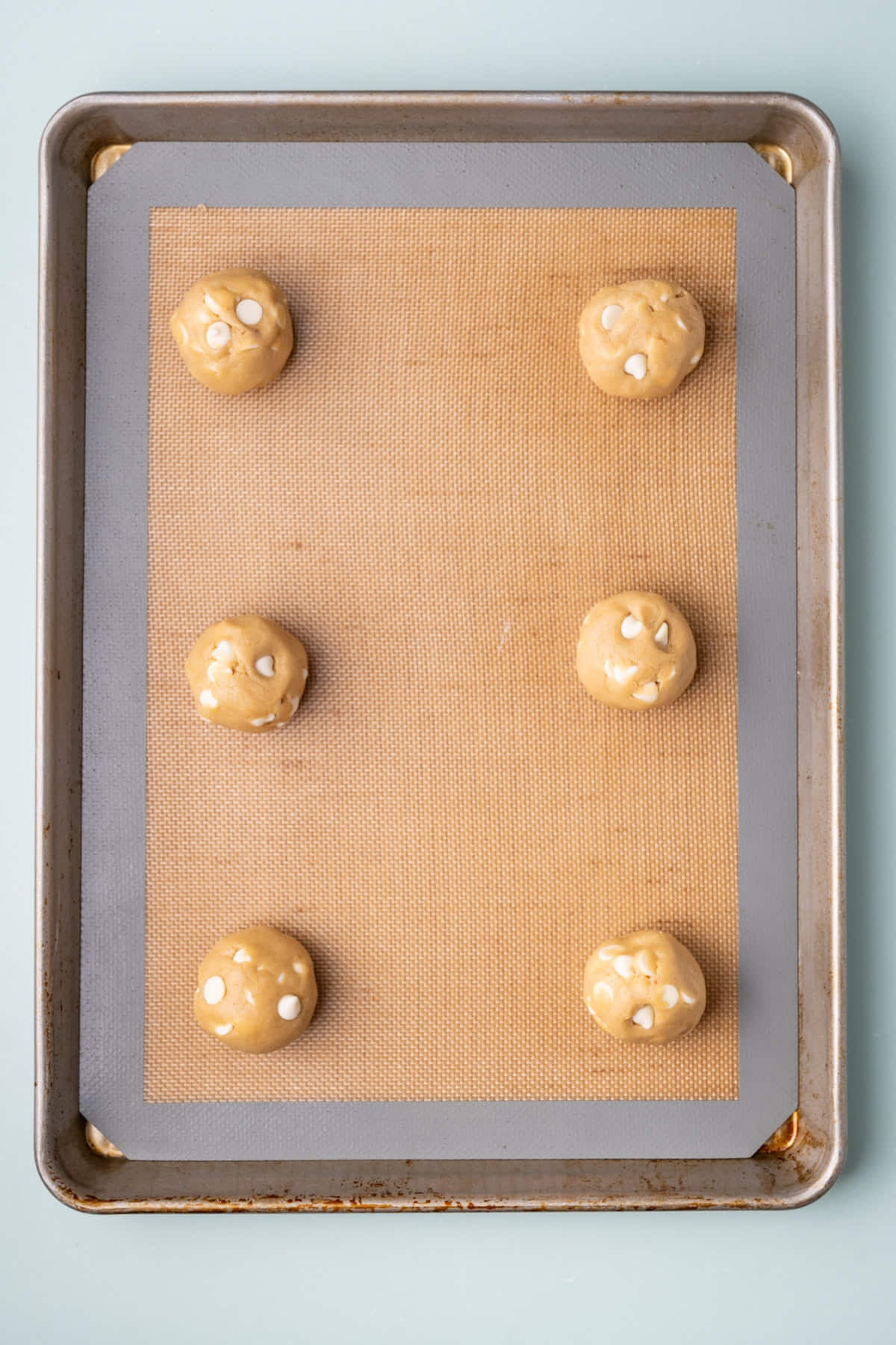 Cookie dough lined up on a baking sheet ready for the oven.