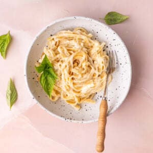 Shallow bowl filled with linguine tossed in Cajun alfredo sauce and garnished with fresh basil.