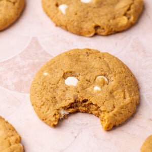 Chewy pumpkin spice cookie with white chocolate chips with a bite taken out of it.