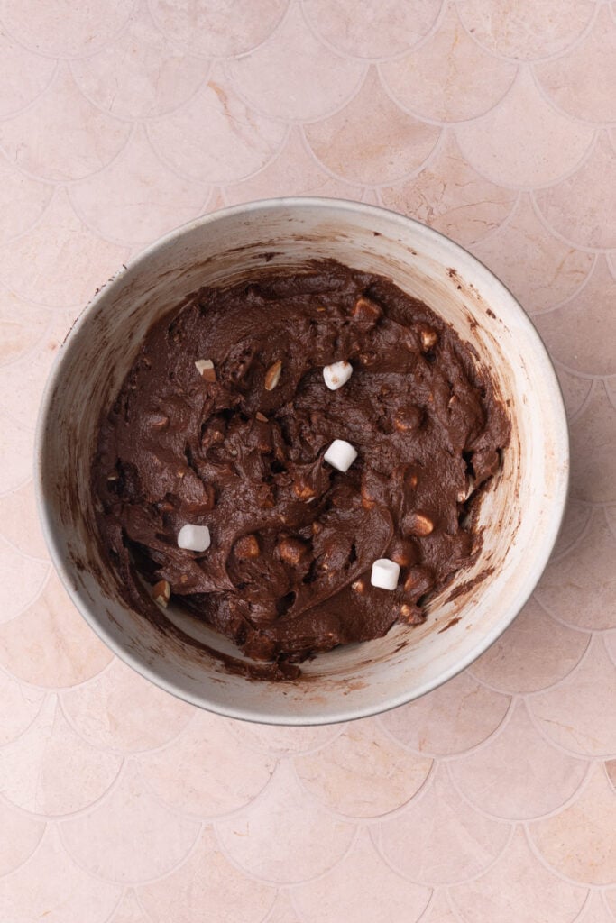 Brownie batter with chopped almonds and mini marshmallows mixed in.