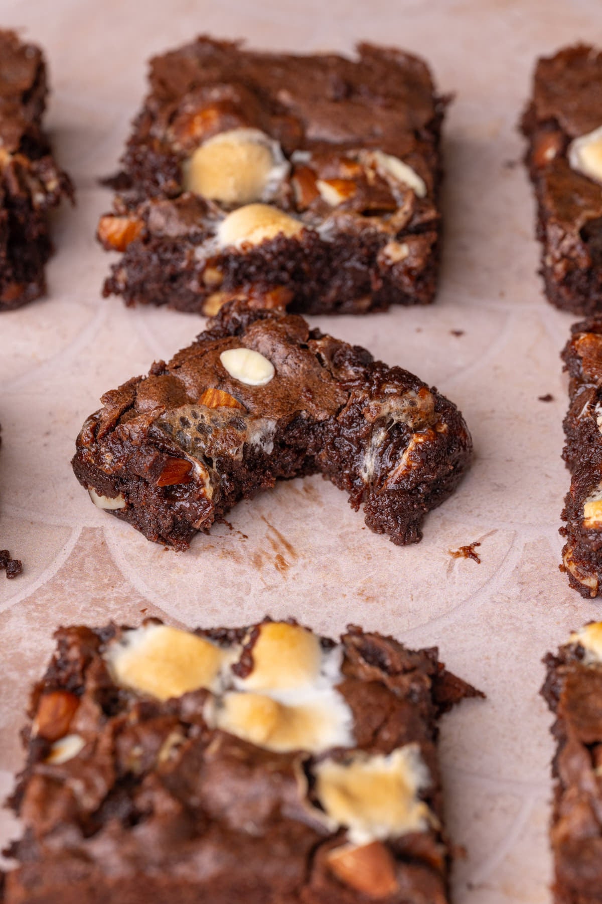 Center brownie with marshmallows and almonds with a bite taken out to show the fudgy interior.