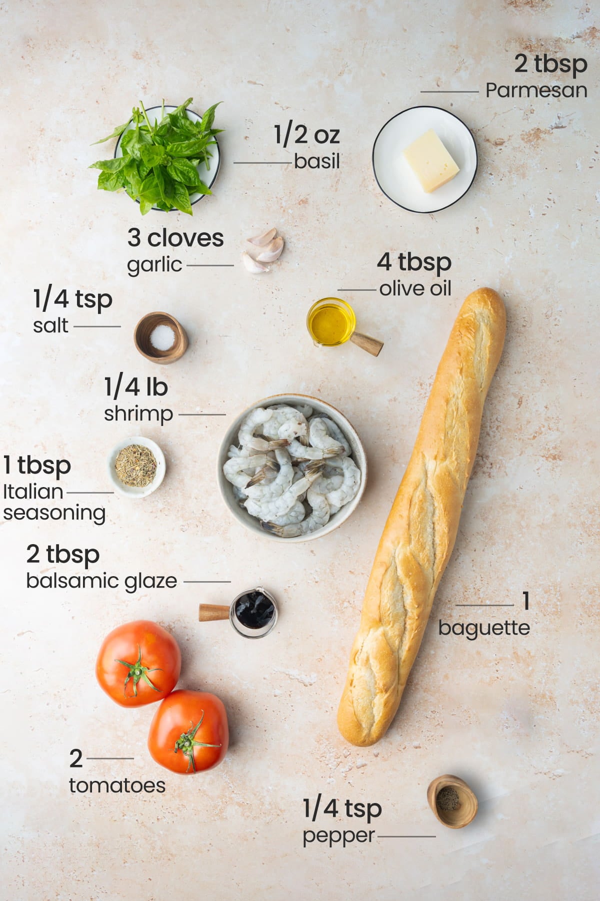 Overhead view of the ingredients for shrimp bruschetta - Parmesan, basil, garlic, salt, olive oil, shrimp, Italian seasoning, balsamic glaze, baguette, tomatoes, and pepper.