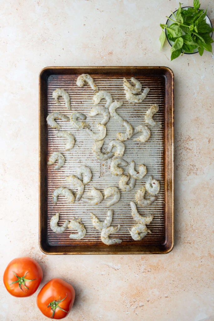 Shrimp tossed with olive oil and Italian seasoning then spread out on a baking sheet to bake in the oven.
