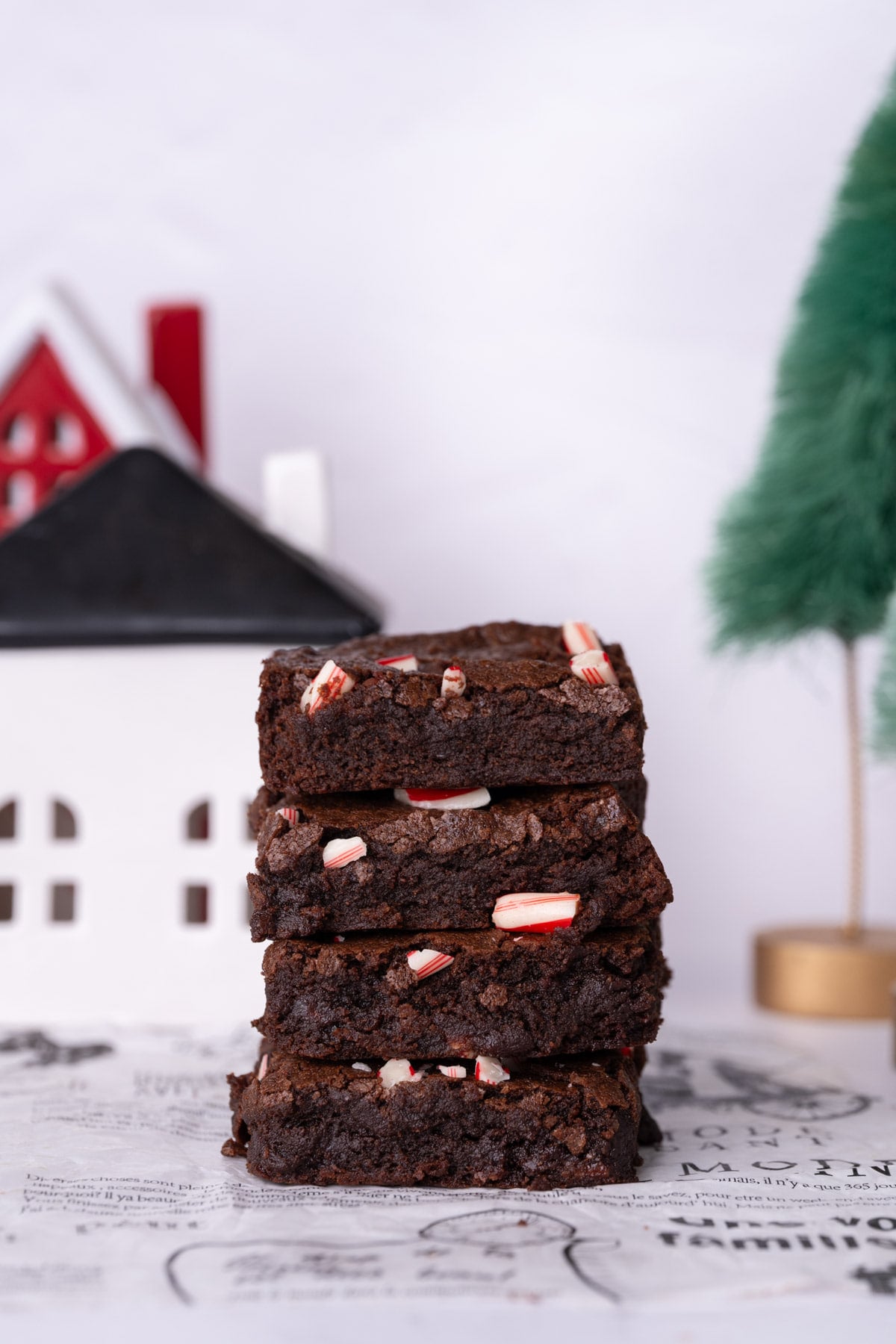Stack of four candy cane brownies with a little Christmas village in the background.