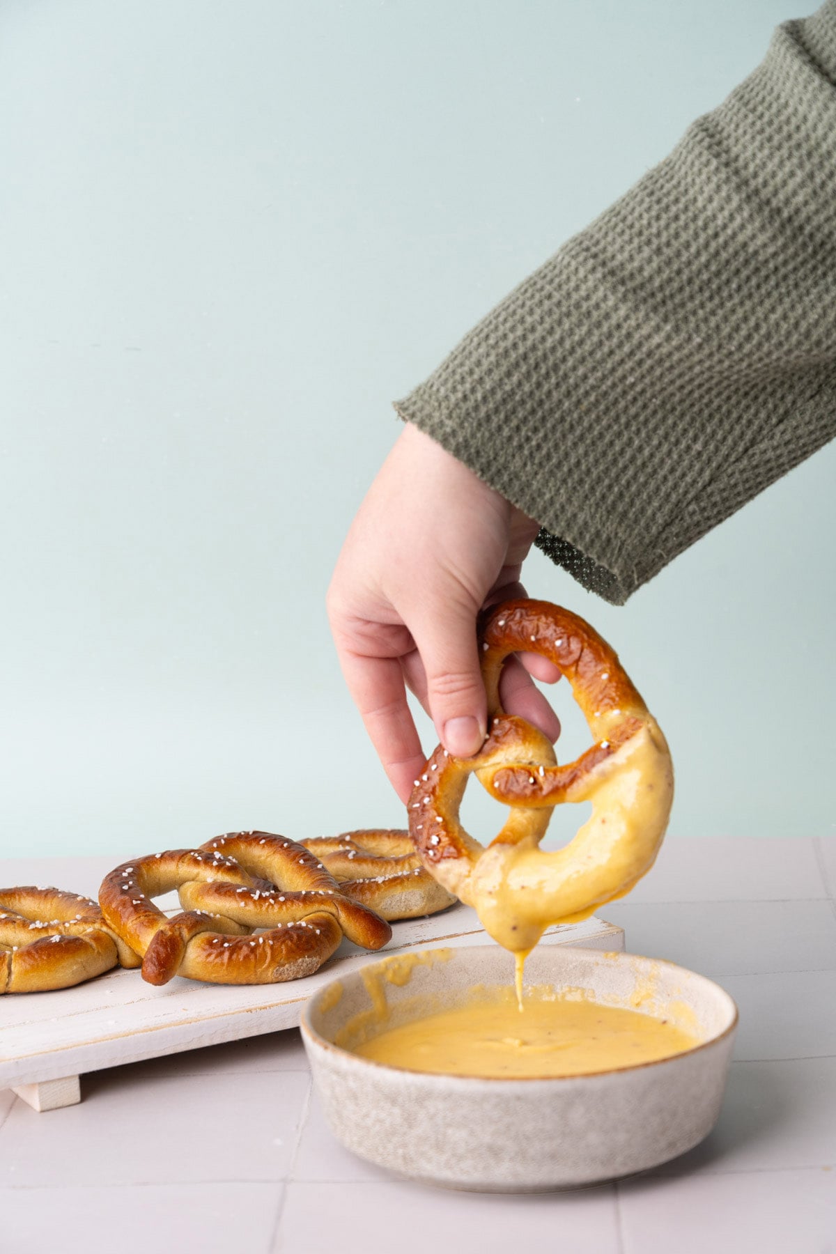 Cheese sauce dripping off a baked soft pretzel.