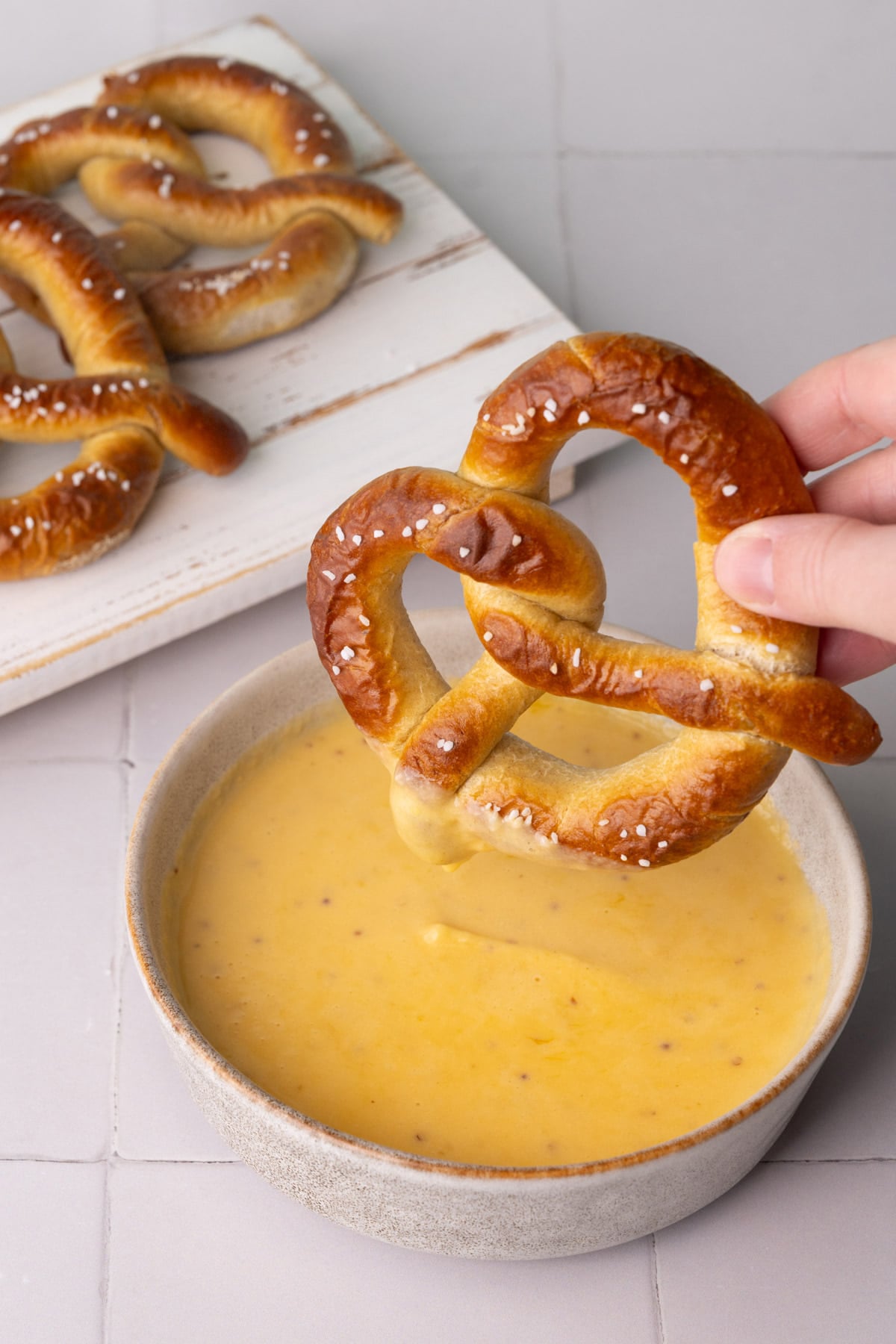 Dunking a soft pretzel into cheese sauce.
