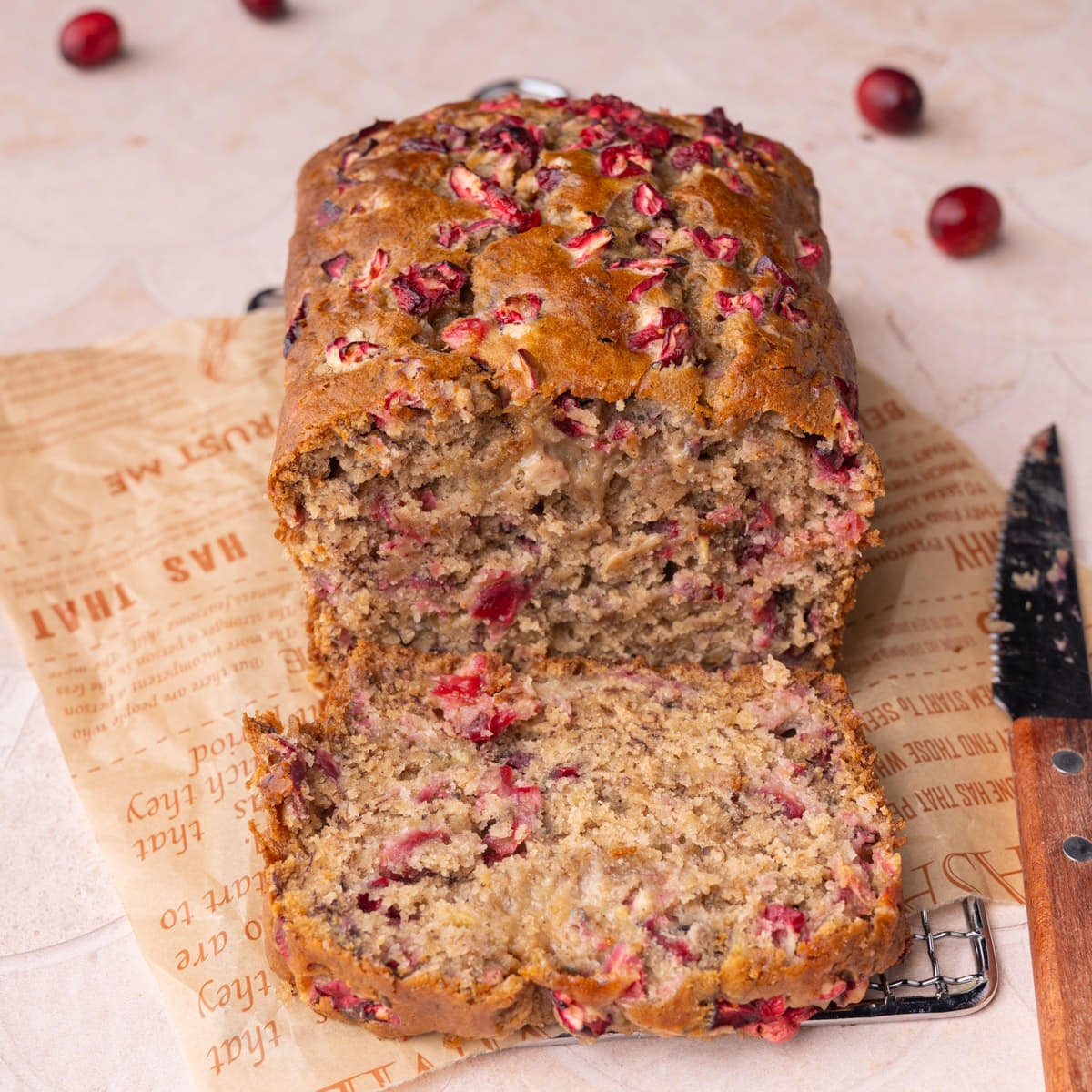 Cranberry Banana Bread Featured Image Loaf of cranberry banana bread with one slice open to show top and inside textures of the bread.