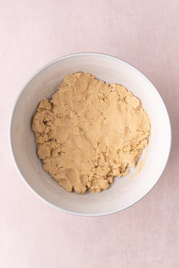 Brown sugar-based cookie dough in a large ceramic mixing bowl.