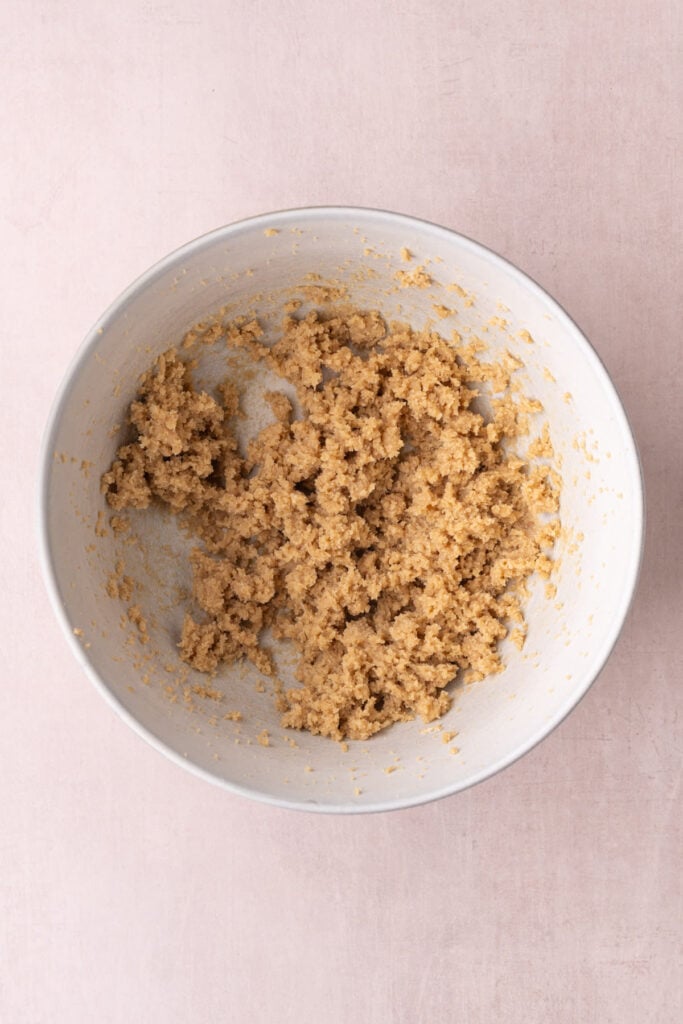 Softened unsalted butter and light brown sugar creamed together until smooth and airy in a ceramic mixing bowl.