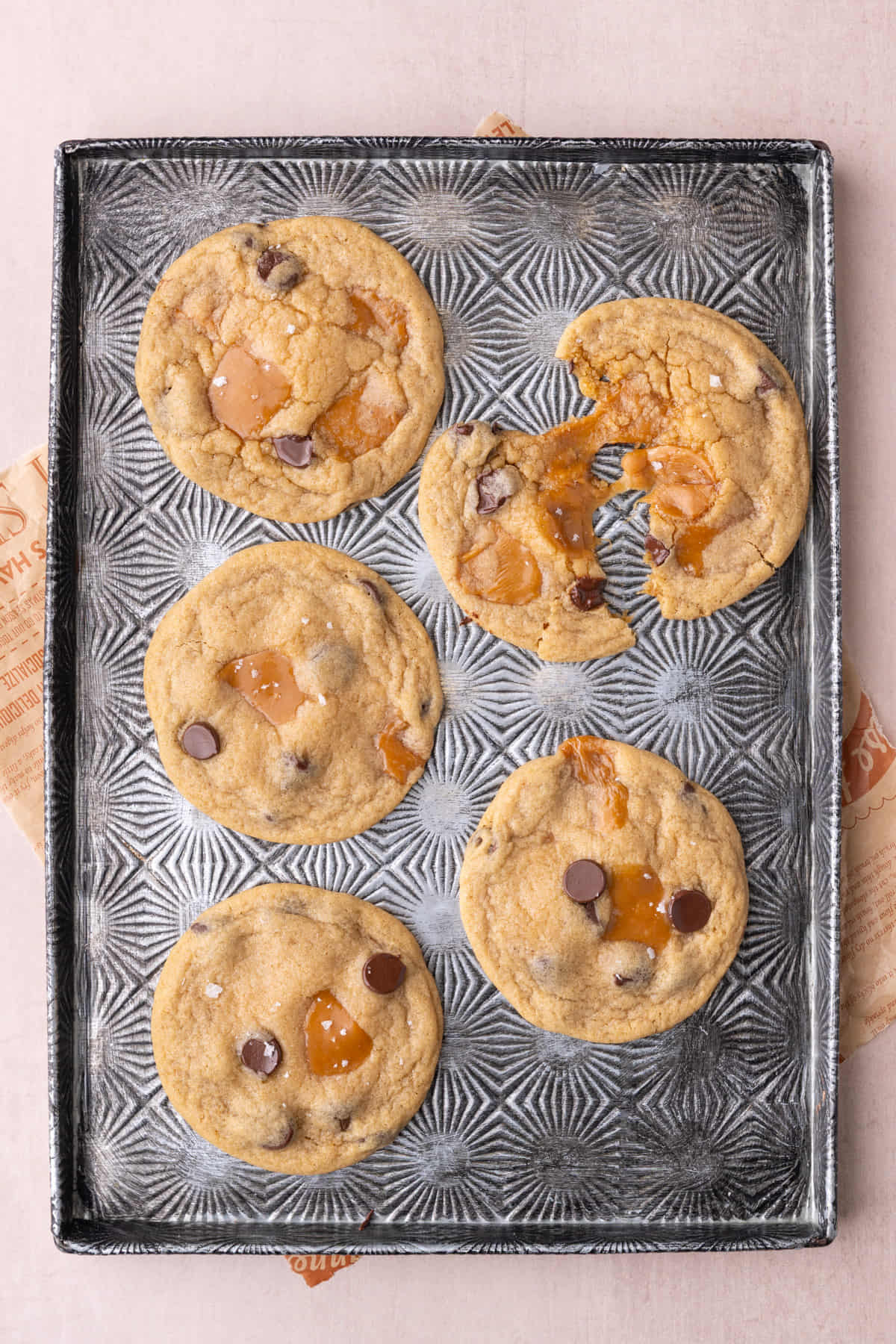 Caramel chocolate chip cookies with one split in half to show caramel pull.
