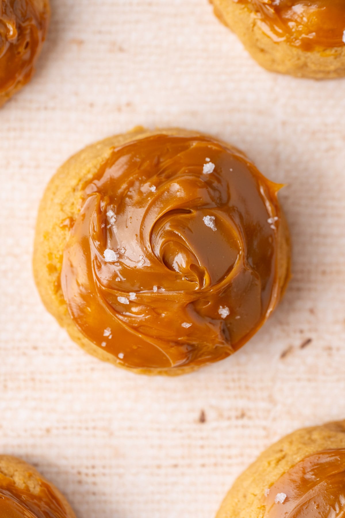 Super close up of a soft and buttery cookie topped with Dulce de Leche and flaky sea salt.