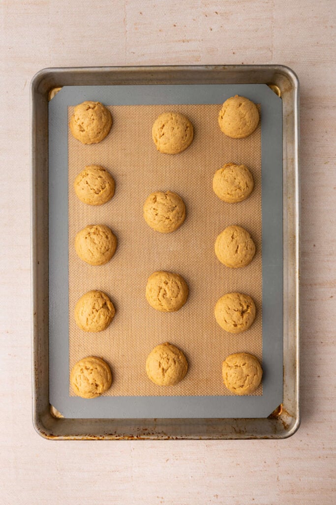Dulce de leche cookies straight out of the oven still cooling on a lined baking sheet.