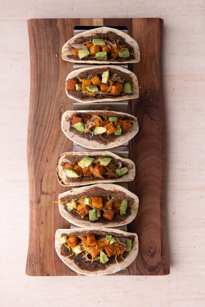 Adding cheese and avocado to sweet potato and black bean tacos.