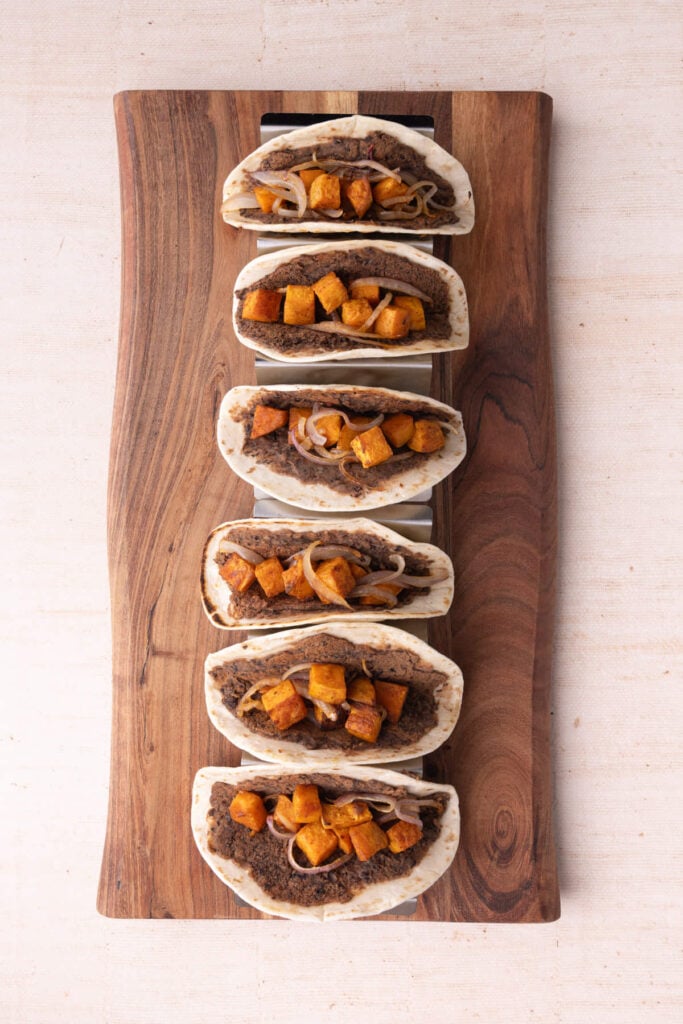 Adding roasted sweet potato and onion to tacos with smashed black beans.