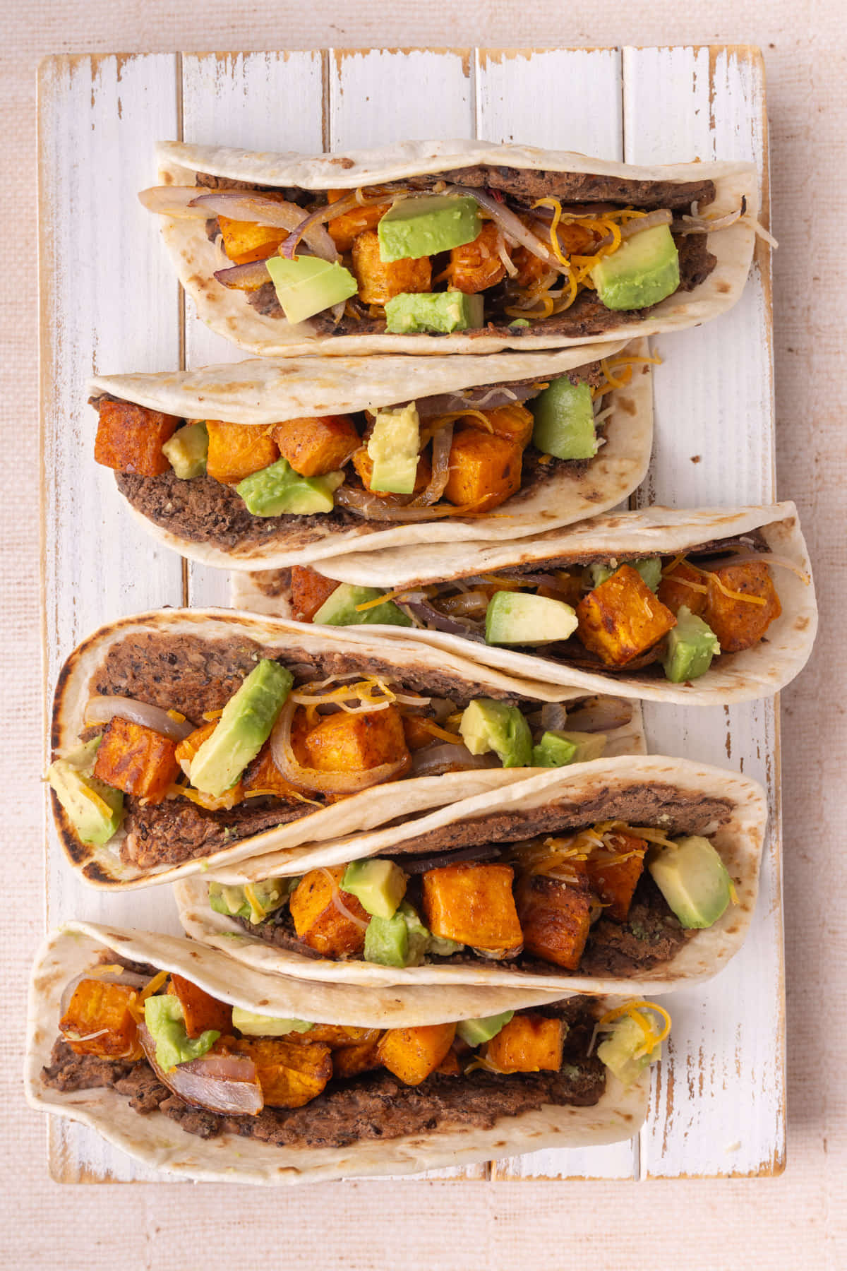 Overhead image of black bean sweet potato tacos lined up in a row.