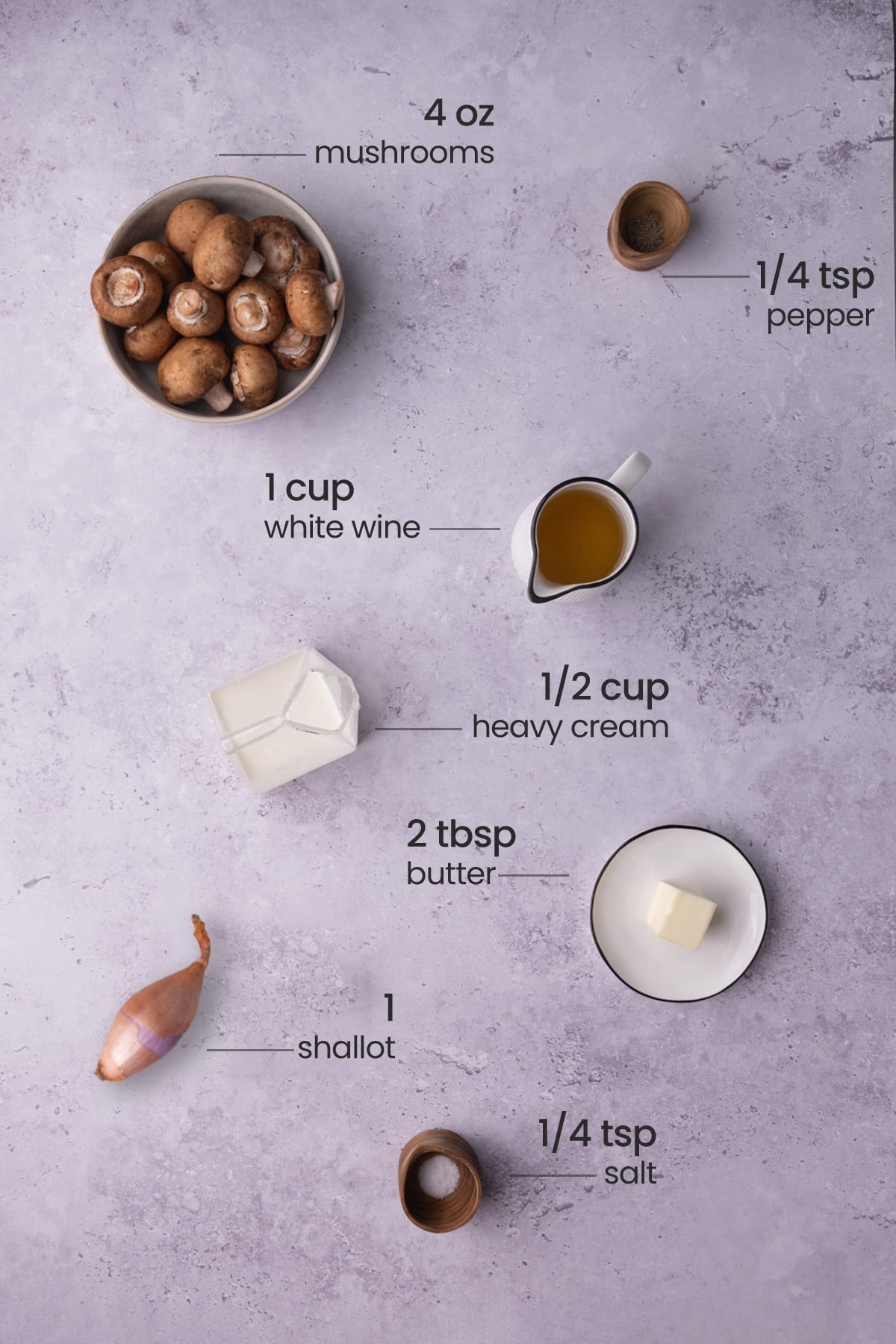 Overhead view of the ingredients needed for white wine mushroom cream sauce - mushrooms, pepper, white wine, heavy cream, butter, shallot, and salt.