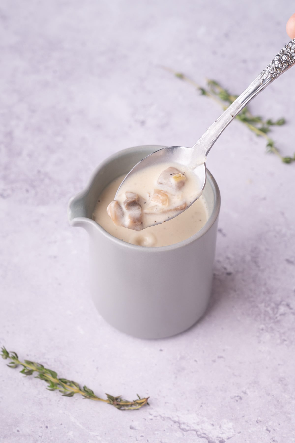 White wine mushroom sauce on a spoon over a creamer.