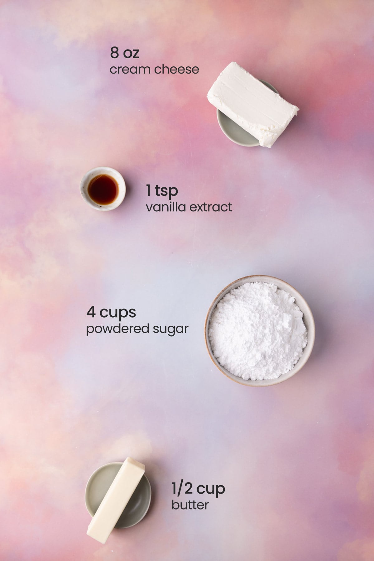 Overhead view of the ingredients needed for brown butter cream cheese frosting - cream cheese, vanilla extract, powdered sugar, and butter.