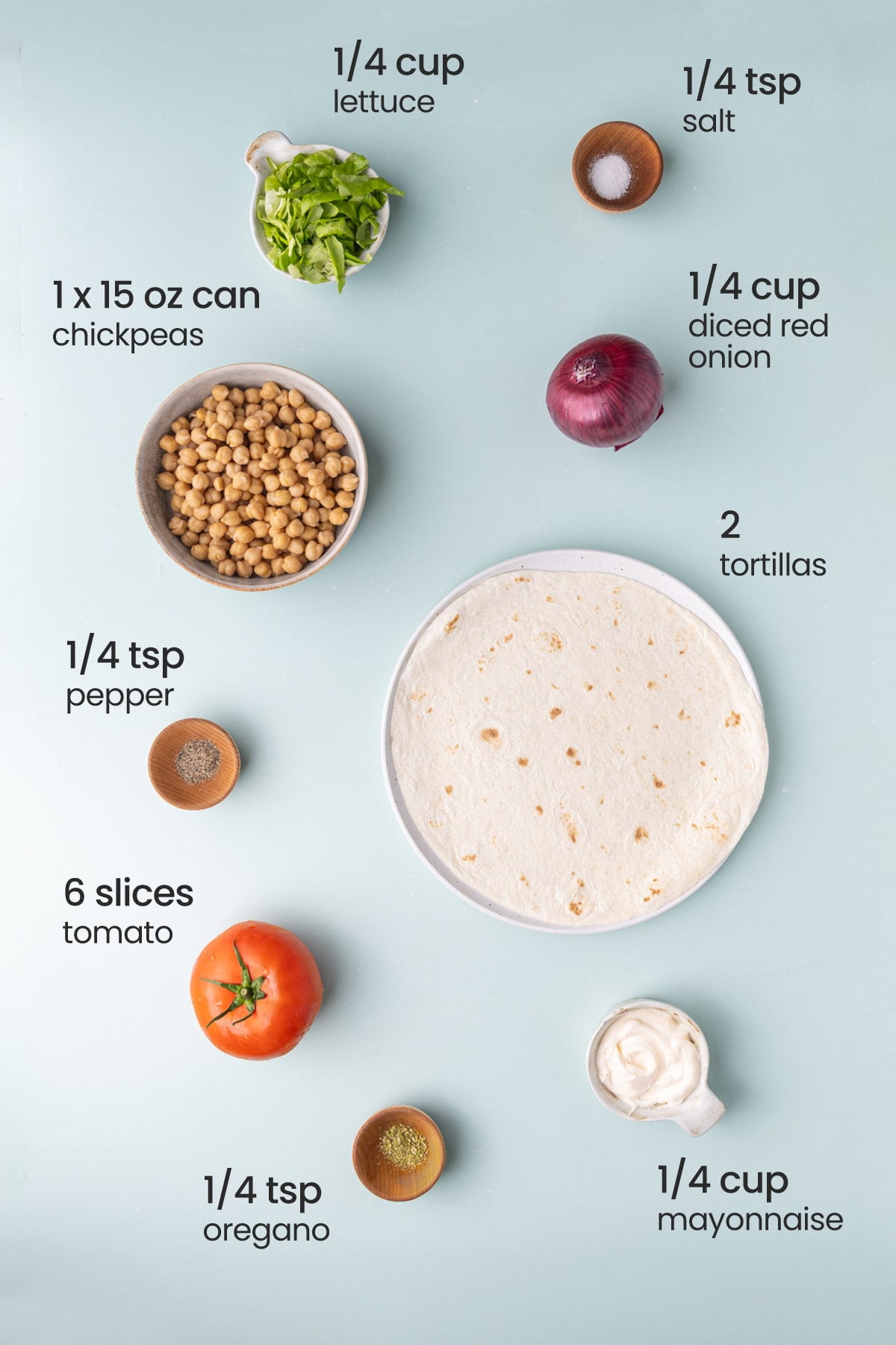 All ingredients needed for a chickpea salad wrap including lettuce, salt, red onion, chickpeas, tortillas, pepper, tomato, oregano, and mayonnaise.