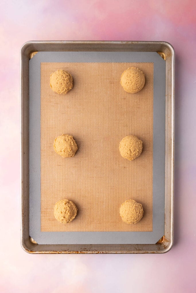 Cookie butter cookie dough shaped into 6 round balls ready to bake in the oven.