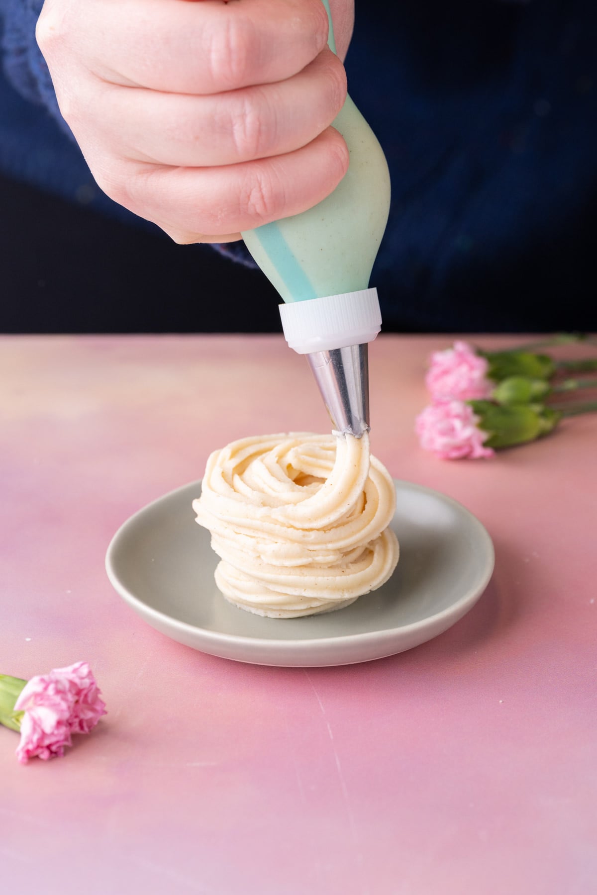 Piping brown butter cream cheese frosting onto a small dish to show texture.
