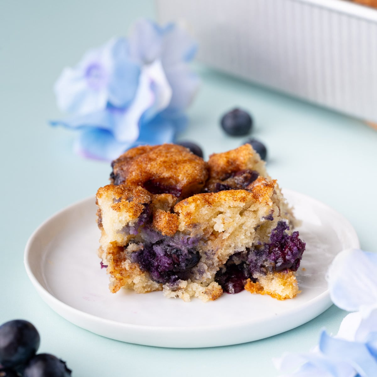 Piece of blueberry coffee cake on a white plate.
