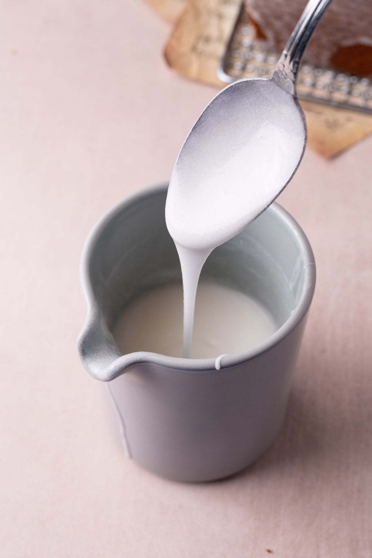 Coconut glaze running off a spoon into a creamer.
