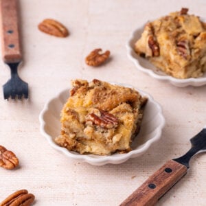 Close up of piece of pecan pie bread pudding with pecan halves in the background.