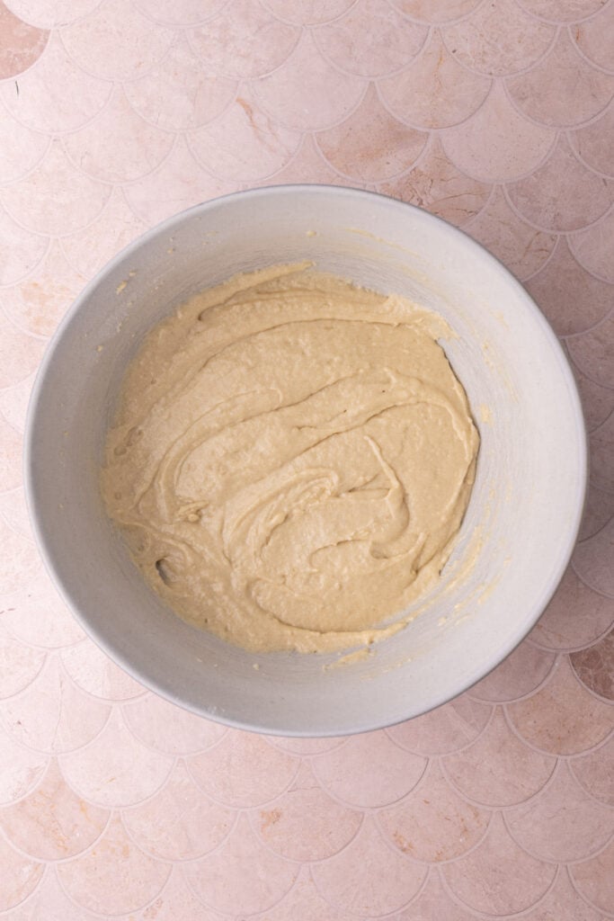 Moist cake batter in a bowl ready to layer with cinnamon sugar in a baking pan.
