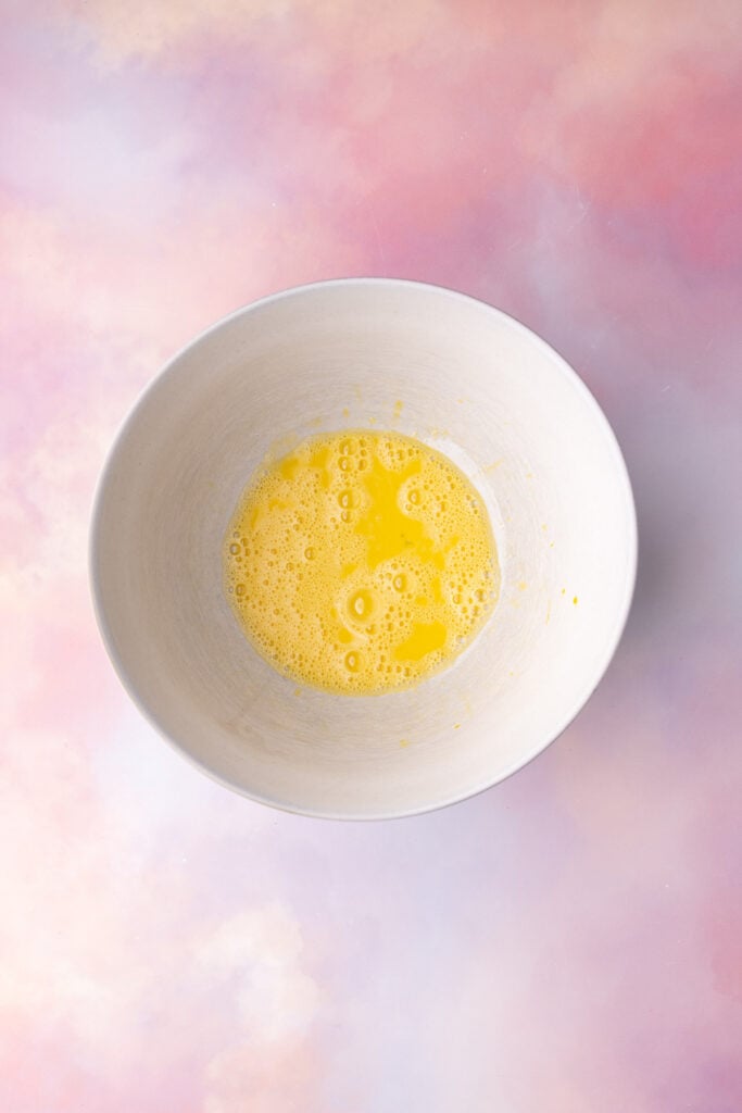 Two eggs beaten until well-combined and aerated in a large mixing bowl.