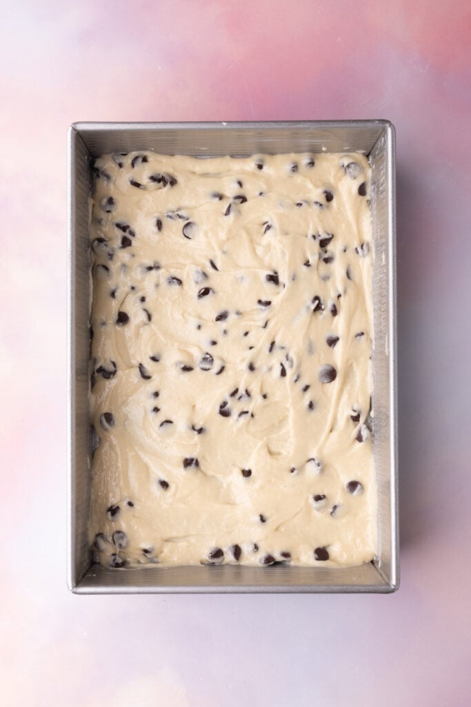 Chocolate chip coffee cake batter in a thin layer in a greased cake pan.