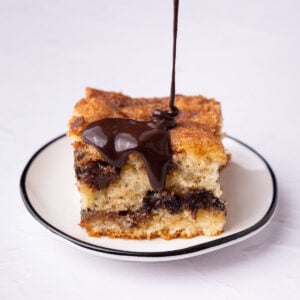 Drizzling chocolate glaze over a slice of chocolate chip coffee cake.