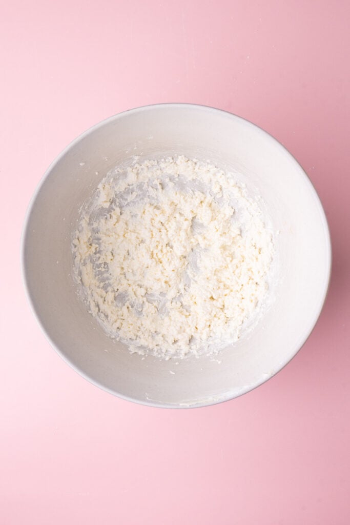 Sour cream, butter, and vanilla extract whipped together to show the process of making sour cream frosting.