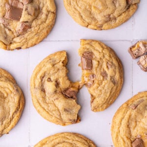 Close up of a cookie with milky way bar split in half and pulled apart to show the gooey caramel inside.