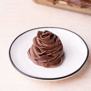 Thick and stable chocolate fudge frosting made with real chocolate piped onto a plate to show how easy it is to work with.