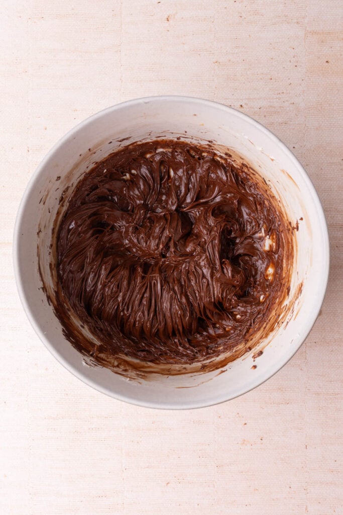 Melted chocolate whipped into softened butter in a large mixing bowl.