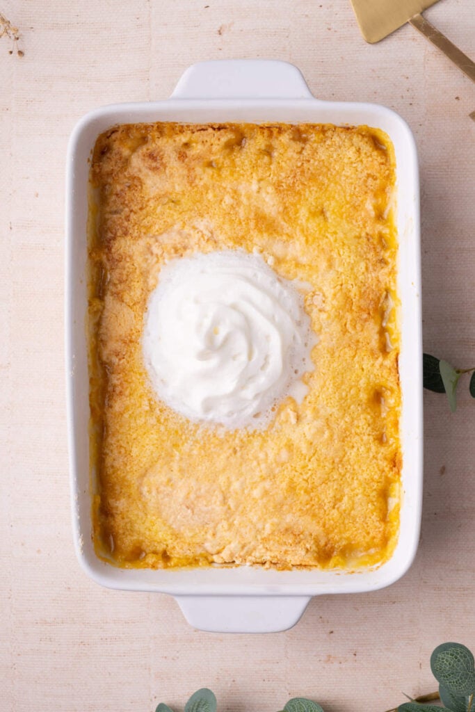Peach dump cake fresh out of the oven with a dollop of whipped cream.