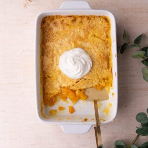 Peach dump cake in a casserole dish with a few servings taken out to show the peachy filling.