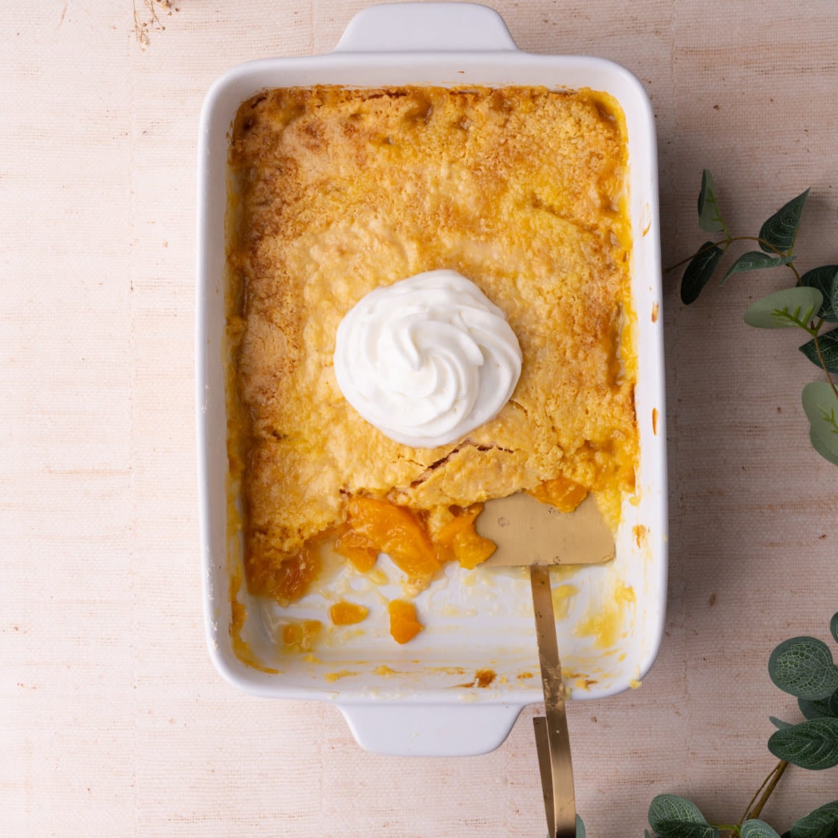 Peach dump cake in a casserole dish with a few servings taken out to show the peachy filling.