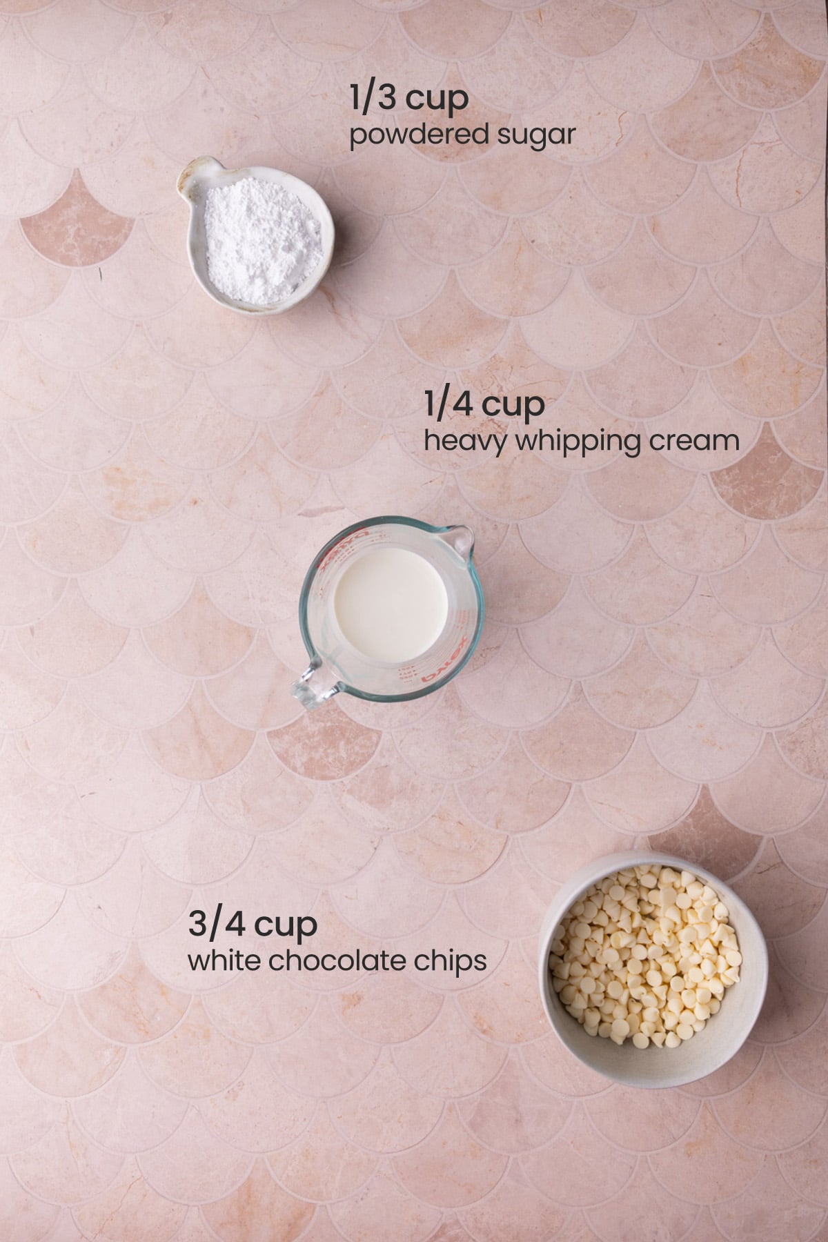 Overhead view of the ingredients needed for pourable white chocolate glaze - powdered sugar, heavy whipping cream, and white chocolate chips.