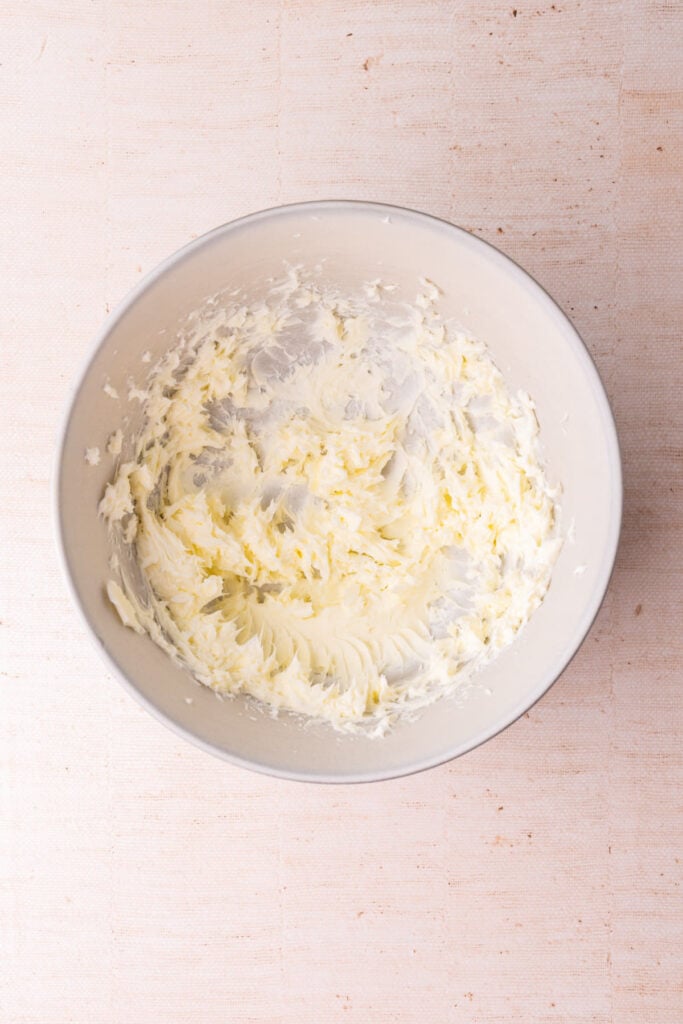 Softened butter whipped with a hand mixer in a large mixing bowl.