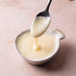 White chocolate glaze running off a spoon into a little dish.