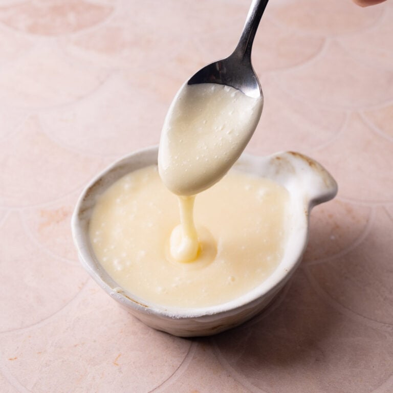 White chocolate glaze running off a spoon into a little dish.