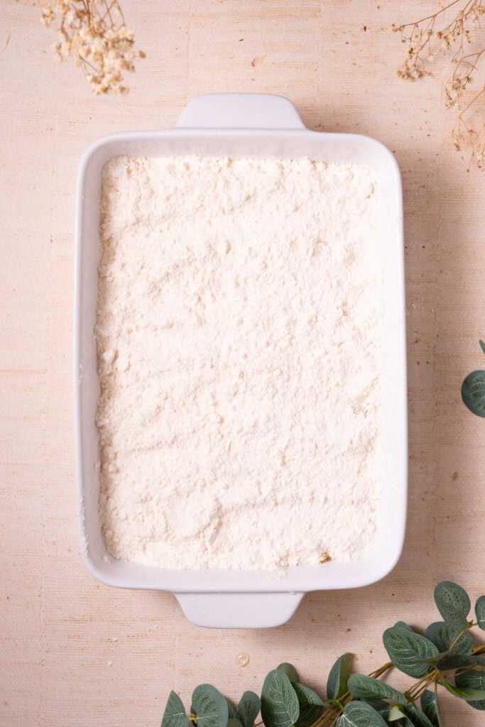 Yellow cake mix layered on top of peach pie filling in a casserole dish.